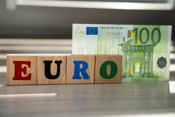 colorful EURO inscription made of wooden blocks and 100 euro banknote. The colors symbolize the diversity of the countries that make up European Union and share common currency