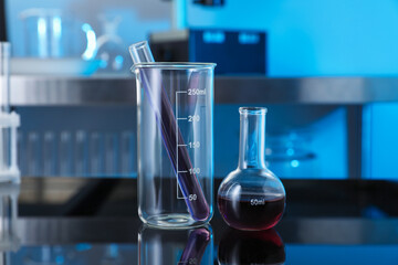 Different glassware with red liquid on table in laboratory, closeup