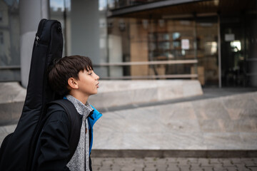 Fototapeta premium Boy carrying guitar case going to music school
