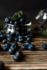 Fresh blueberries scattered on a rustic wooden surface. Still life composition with soft lighting and a blurred background. Concept of healthy eating, organic food, and natural freshness.