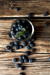 Fresh blueberries scattered on a rustic wooden surface. Still life composition with soft lighting and a blurred background. Concept of healthy eating, organic food, and natural freshness.