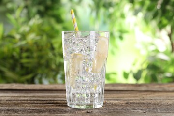 Refreshing water with lemon and ice on wooden table against blurred background