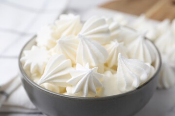Delicious meringue cookies in bowl on table, closeup
