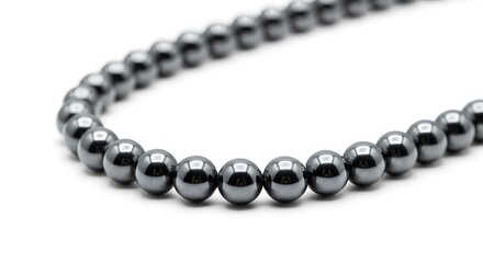 Close up of a strand of dark gray oval beads forming a curve isolated on white background