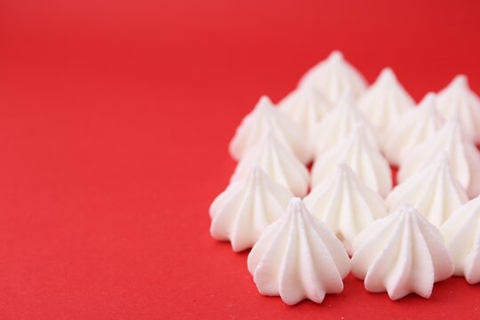 Delicious meringue cookies on red background, closeup. Space for text