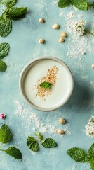 Overhead Bowl with White Liquid, Sesame Seeds and Mint on Textured Blue Surface