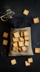 Square Crackers in Burlap Sack with Black Topping on Black Textured Backdrop