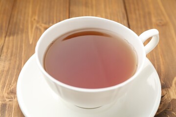 Cup of aromatic black tea on wooden table, closeup