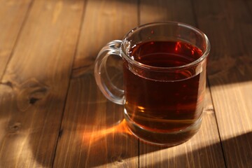 Aromatic black tea in cup on wooden table, closeup. Space for text