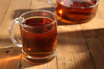 Aromatic black tea in cup on wooden table, closeup