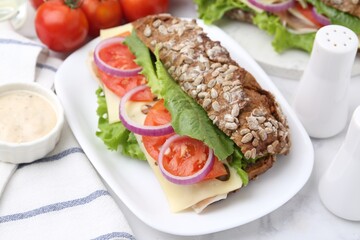 Tasty ciabatta sandwich with cheese and vegetables on white marble table, closeup