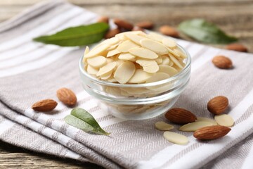Fresh almond flakes and whole nuts on table, closeup