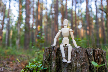 A wooden figure of a man sits on a tree stump and waits