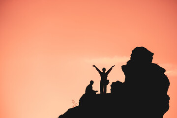 A man and a woman are sitting on a rock, looking up at the sky