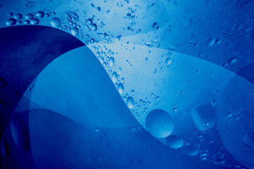 Abstract background of oil bubbles in blue liquid creating smooth shapes.