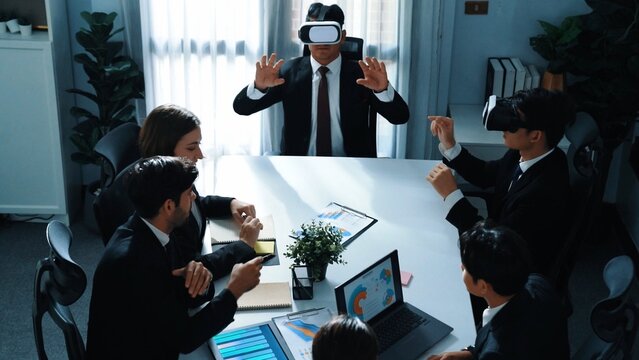 Top view of manager working on laptop and sending data analysis to business people by using VR glass headset while diverse team planning marketing strategy and looking at financial graph. Directorate.