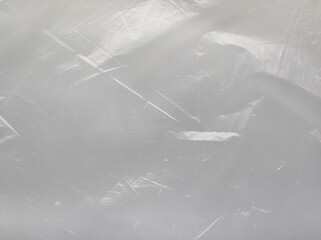 A light gray textured background. A transparent, worn plastic bag with with subtle scratches and imperfections.