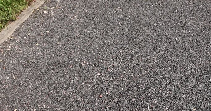 a narrow walking path in the park made of finely crushed rubble, not a wide path for pedestrians to walk in the park in sunny weather