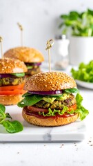 Three veggie burgers on buns, topped with lettuce, tomato, onion, and avocado