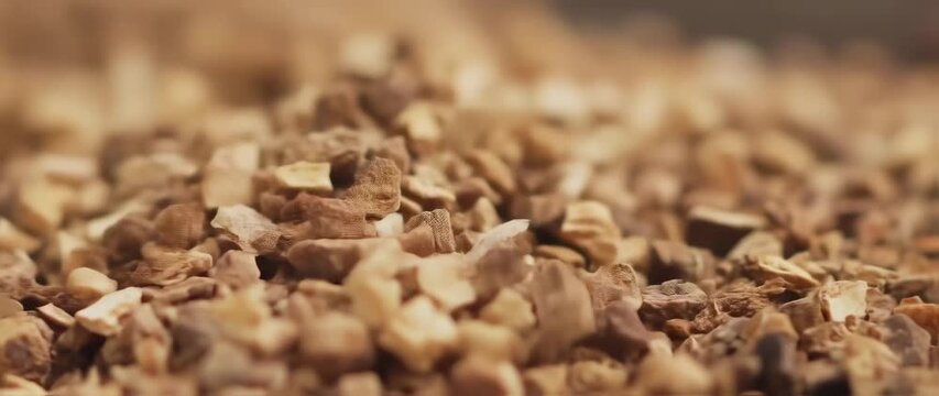 Slow motion close-up of dry ginger granules pouring on the floor for health benefits and medicinal