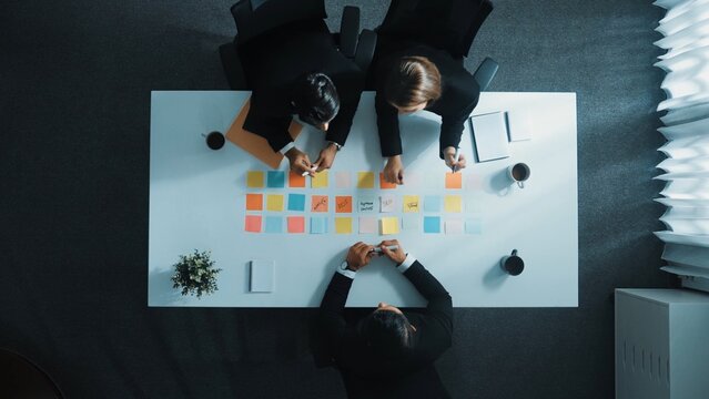 Top view of professional business team planning marketing strategy. Skilled group of diverse business people writing and sharing creative idea on sticky notes and discuss about plan. Directorate.