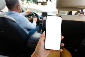 Woman passenger holding smartphone with blank screen, sitting on backseat in auto while driver man driving car, mockup. Taxi service app concept