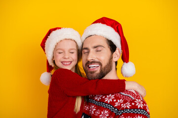 Fototapeta premium Joyful father and daughter wearing holiday Santa hats and red sweaters sharing a cheerful holiday bonding moment