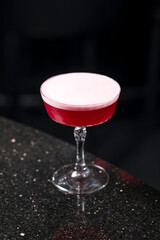 Classic clover club raspberry gin alcoholic cocktail in dark bar atmosphere with bokeh lights
