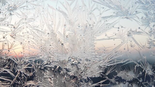 Ice patterns on window against backdrop of city skyline at dawn, close up. Water and condensation crystallize on glass in subzero temperatures.