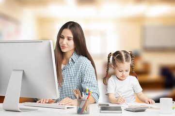 Happy busy mother working with a child on computer