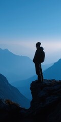 Fototapeta premium Silhouette of male hiker overlooking majestic mountain landscape at dawn