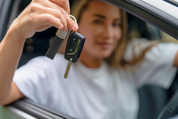 Woman smiles while holding car keys at the driver's seat of a vehicle