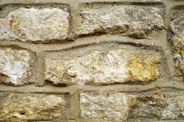 Rough-hewn stone wall in the Cotswolds, England featuring irregularly shaped sandstone blocks....