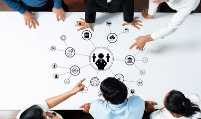 A business team collaborates over a table, analyzing data and discussing strategies while surrounded by visual aids. The scene represents teamwork and innovation. Trope