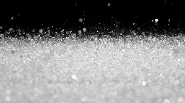 Abstract macro image of a cluster of glistening, white granules floating in the air against black backdrop