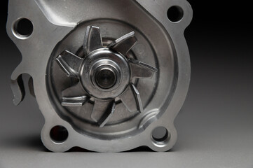 Top-quality parts for your car. Car maintenance. New water pump for a car's engine cooling system on a gray gradient background.