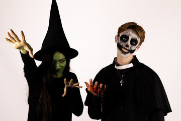 people, dressed as witches, stirring a bubbling cauldron over a crackling fire
