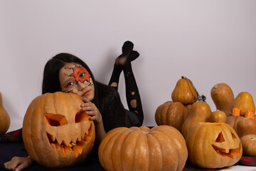 Girl with face painted as pumpkins, smiling brightly in a Halloween costume