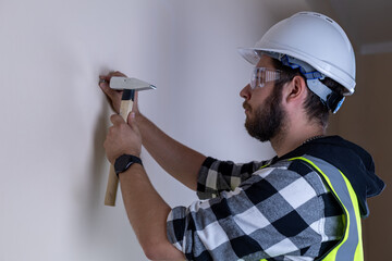 Man in hard hat and safety vest painting a wall