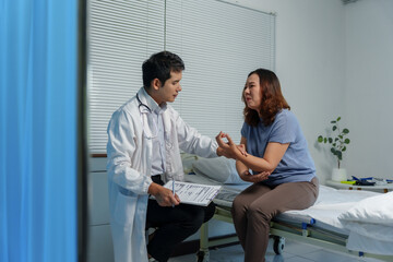 Fototapeta premium Healthcare professional examining woman's painful arm, discussing symptoms during medical consultation in hospital clinic