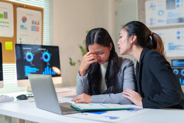 Business woman experiencing work related stress and burnout, receiving comfort and support from a compassionate colleague in office
