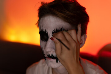 a young guy gets makeup for the Halloween holiday.