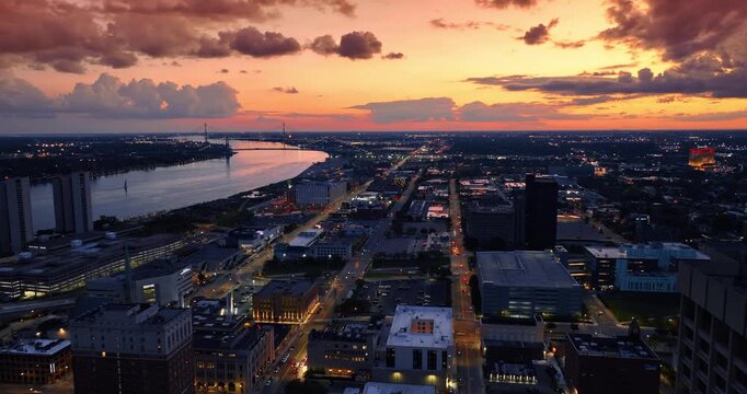 Moving over the city scenery along the Detroit River at dusk time. Amazing orange sky with cumulus clouds at backdrop.