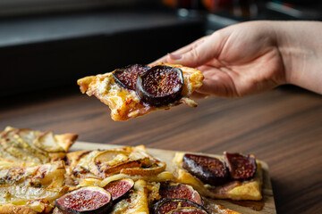 Hand holding slice of fig puff pastry tart