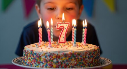 A young boy blowing out candles on a birthday cake celebrating his seventh birthday.
