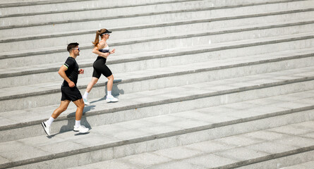 Couple jogging down stairs during workout in urban area