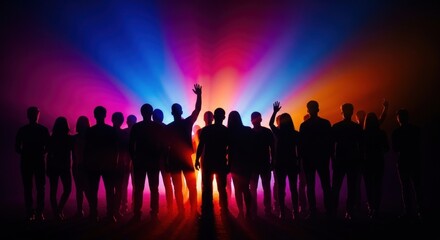 Silhouetted crowd with raised hands stands before a vibrant display of colorful light beams.