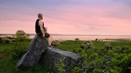 Male hiker sitting on rocks overlooking scenic Corrib Lake in Galway Ireland during sunset adventure travel landscape nature photography