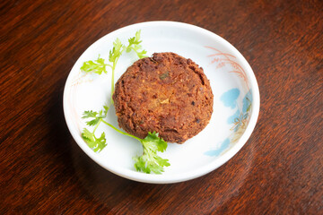 Shami Kebab or Shallow Fried Meat Patty with Coriander Garnish in plate side view of bangladeshi food