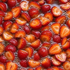 Close up overhead view of fresh ripe strawberries sliced and whole glistening in natural light creating a vibrant red fruit background